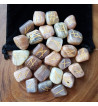 Moonstone rune set with Elder Futhark runes in gold lettering.  Set of 25 stones includes a black rune bag.